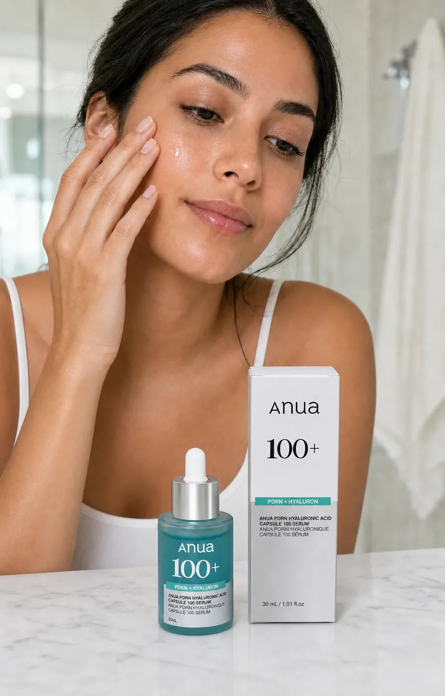 Mujer tocando suavemente su mejilla junto al frasco y la caja de Anua PDRN Hyaluronic Acid Capsule 100 Serum